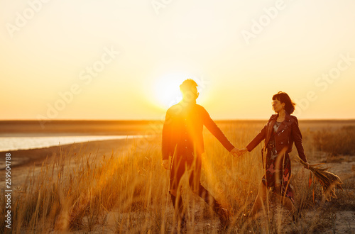 Enjoying time together.  Stylish and loving couple enjoying each other by the sea. The couple is young and in love. The concept of youth, love and lifestyle. Beautiful sunset on a summer day.