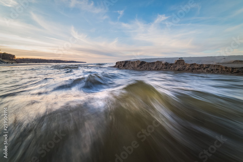 Close-up view of the waves of the fast stream on the shore of the Baltic sea at sunset