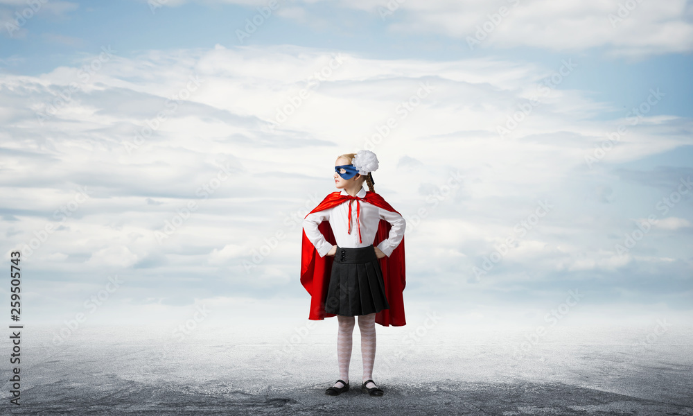 Girl power concept with cute kid guardian against cityscape background . Mixed media