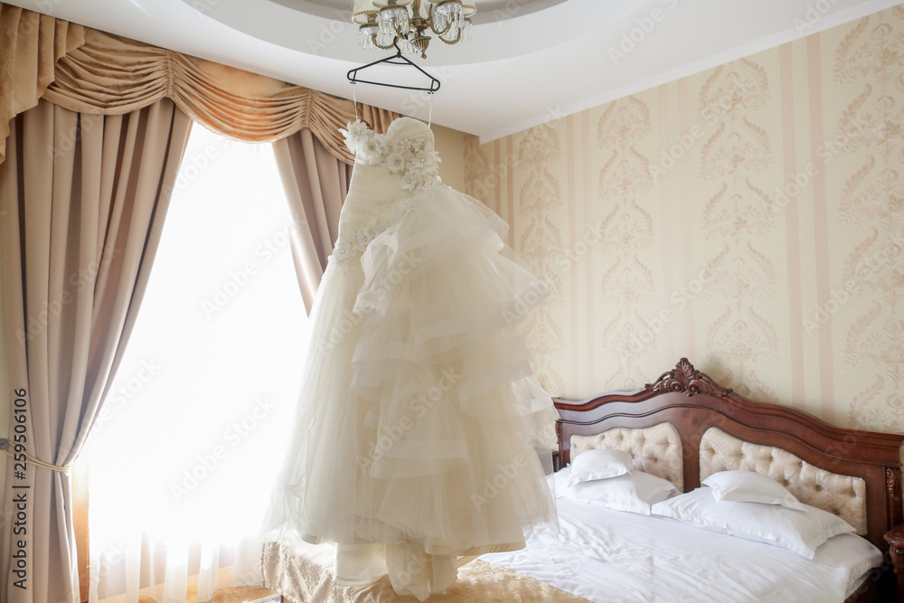 Bride's wedding dress hanging on a chandelier Bride's wedding dress hanging on a chandelier