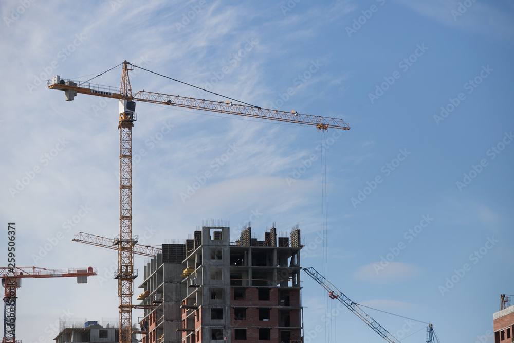 Construction of a multi-storey residential complex. Crane near the building under construction. Background construction site.