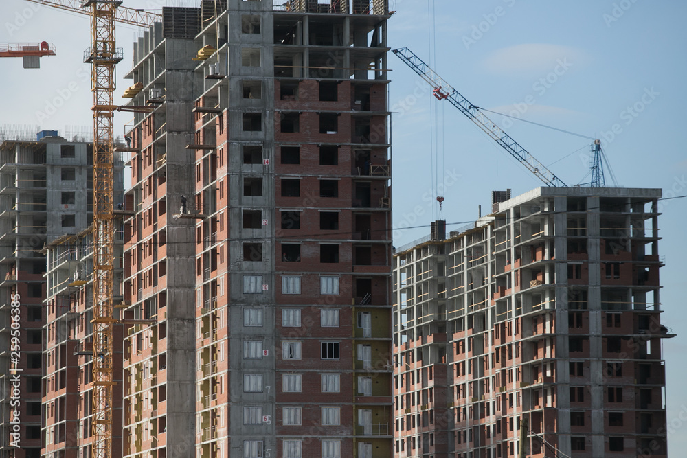 Construction of a multi-storey residential complex. Crane near the building under construction. Background construction site.