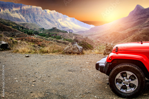 Red summer car on road and mountains landscape 