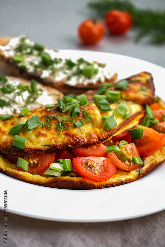 Omelette with cherry tomatoes, toasts with cream cheese and greenery