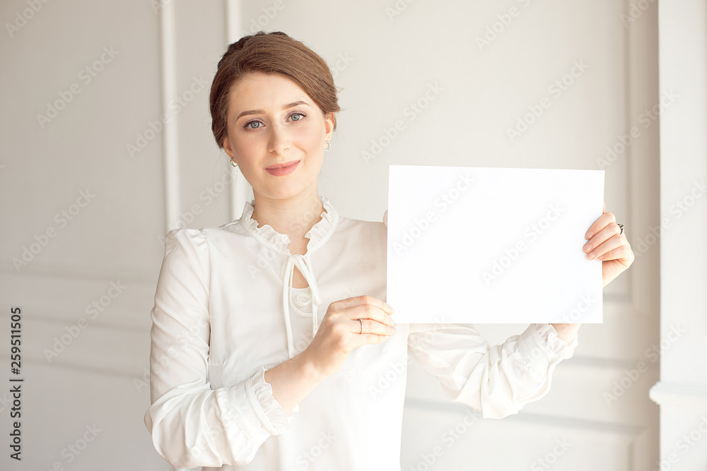 young smiling woman holding a blank sheet of paper for advertising.Girl showing banner with copy space young smiling woman holding a blank sheet of paper for advertising.Girl showing banner with copy space