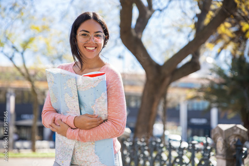 Happy pretty young woman holding paper map outdoors