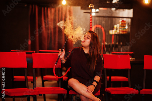 Asian girl smoke hookah at lounge bar.