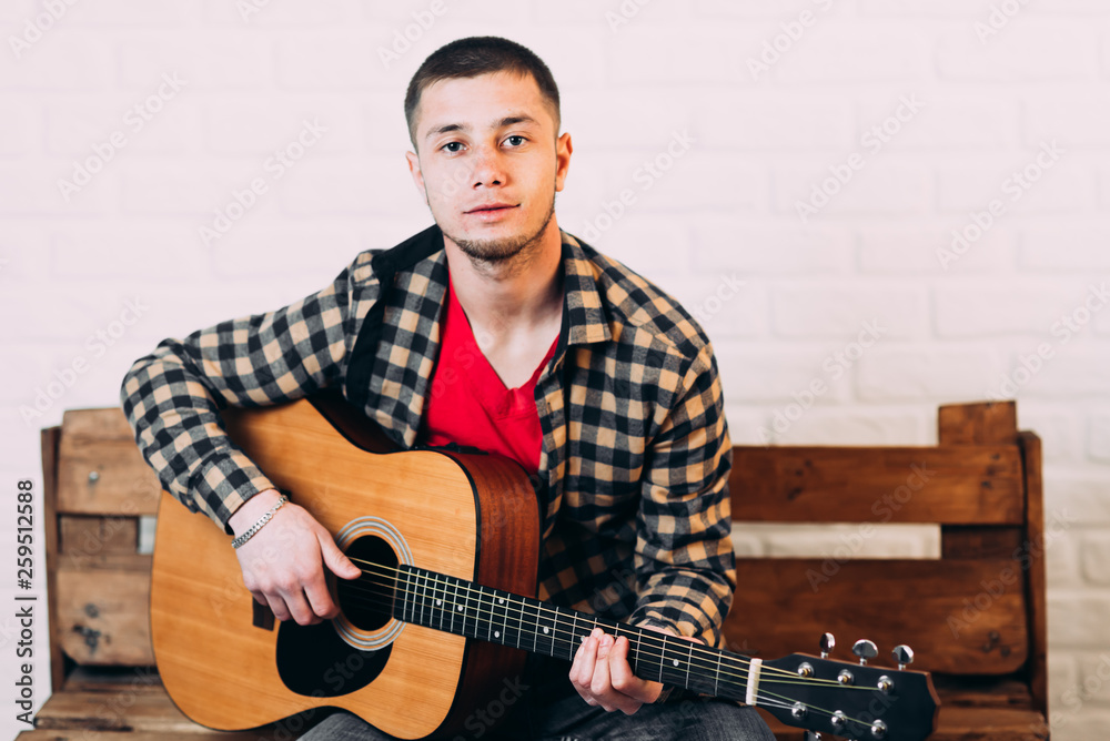 Obraz premium Handsome mature man in casual clothes is smiling while playing guitar at home