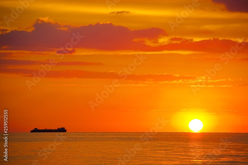 orange sunset on the sea with a ship on the horizon
