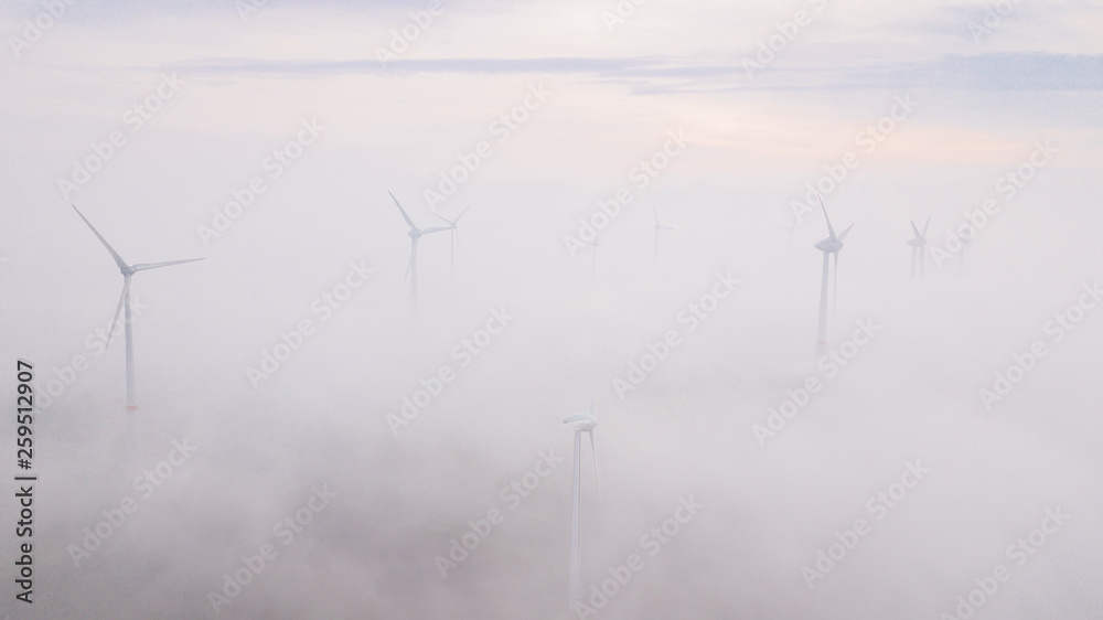 Windmills in the fog at sunrise. Wind turbine from aerial view. Sustainable development, environment friendly. Windmills in the fog at sunrise. Wind turbine from aerial view. Sustainable development, environment friendly.