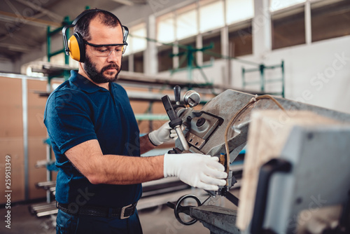 Factory worker operating band saw cutting machine photo