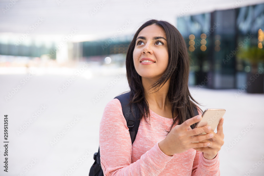 Positive dreamy girl using gadget and looking up