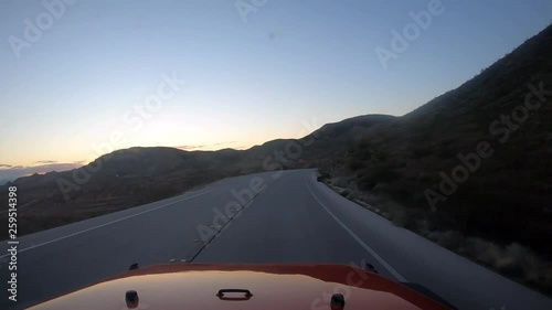 Wallpaper Mural Driving toward the sunrise in a red vehicle in the desert with light from headlights and mountains visible in silhouette; passing a truck towing a camping trailer Torontodigital.ca