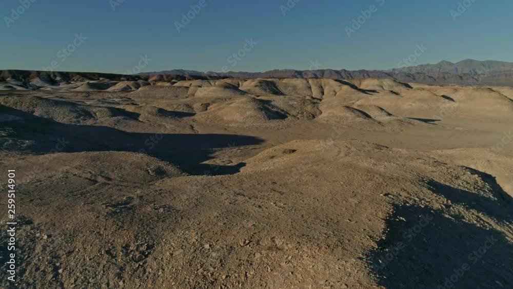 Slow, aerial view moving over dry, barren mudstone embankments in a desert Slow, aerial view moving over dry, barren mudstone embankments in a desert