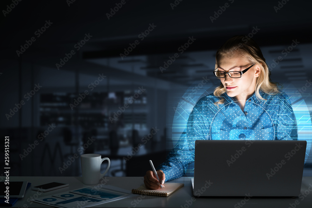 Beautiful blonde in dark office working on laptop and getting net access