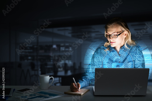 Beautiful blonde in dark office working on laptop and getting net access