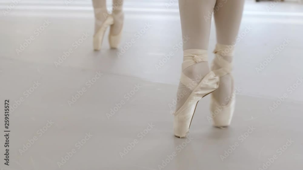 Close-up slow motion video of several ballerina's pointe shoes while practising pointe techniques in a ballet studio. Close-up slow motion video of several ballerina's pointe shoes while practising pointe techniques in a ballet studio.