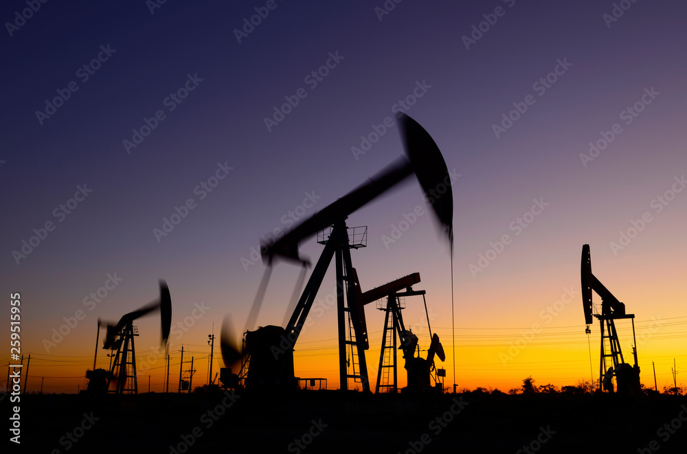 Oil pumps in action, silhouetted against the setting sun