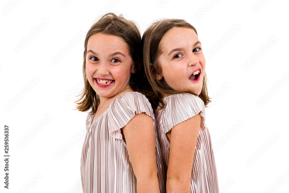 Identical twin girls are turned facing back to back. Identical twin girls are turned facing back to back.