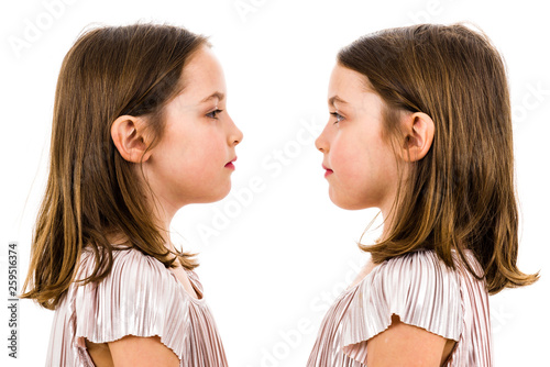 Identical twin girls are looking at each other and smiling. photo