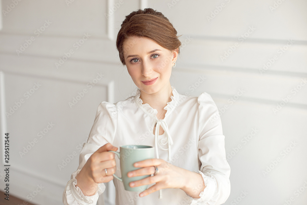 Attractive young woman in casual clothes is holding a cup, looking away and smiling, on white background. Attractive young woman in casual clothes is holding a cup, looking away and smiling, on white background.
