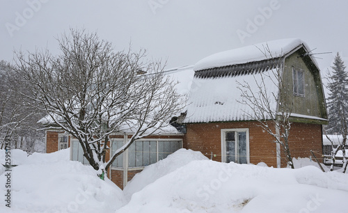 Village house, covered with a lot of snow during snowfall.