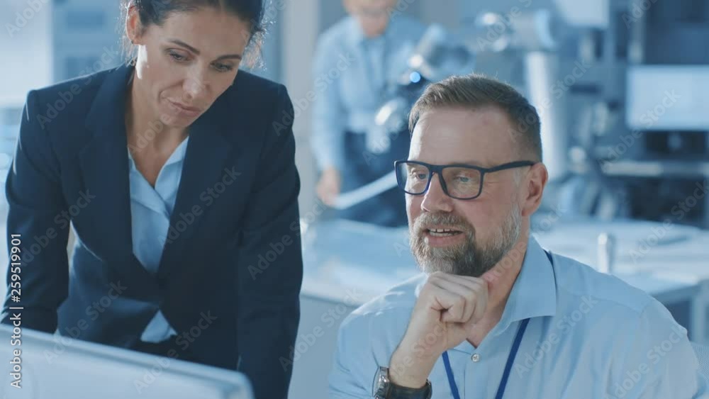 Female Chief Engineer Talks with Electronics Specialist, Explaining Things, He Works on Desktop Computer, they Find Solution and High Five Each Other Cheerfully Celebrating. Modern and Bright Office