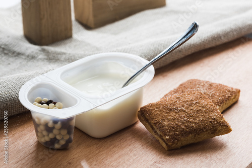 Yogurt with chocolate balls. Double plastic cup with white yogurt and sweet cinnamon cookies.