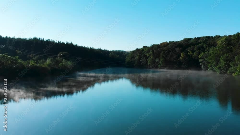 Early morning low drone shot over glossy lake with some fog and birds Early morning low drone shot over glossy lake with some fog and birds