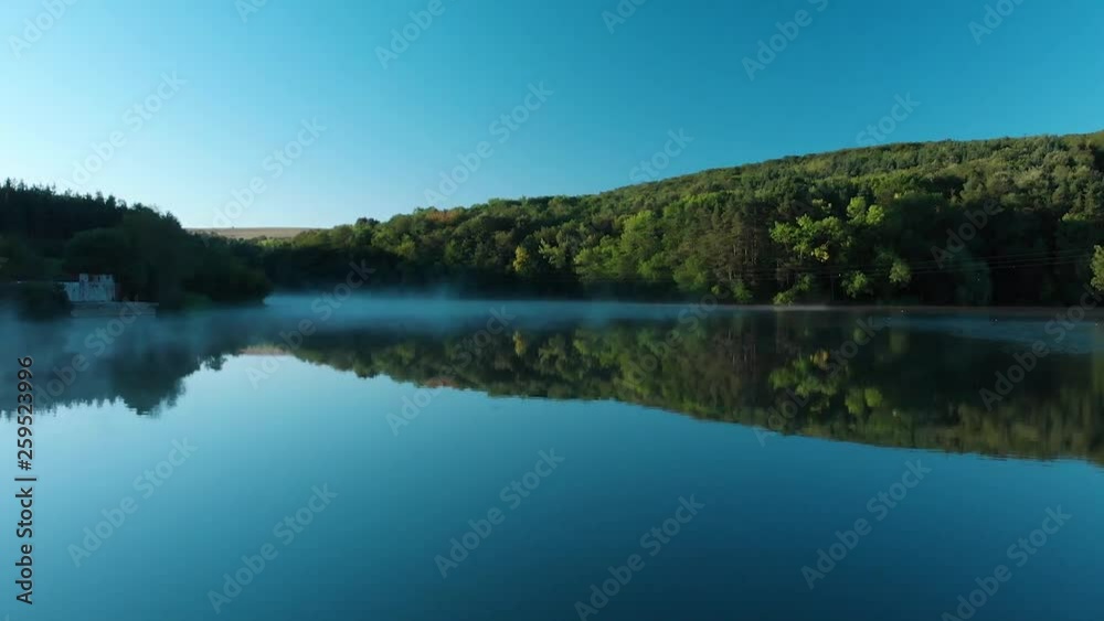 Early morning low drone shot over glossy lake and some fog Early morning low drone shot over glossy lake and some fog