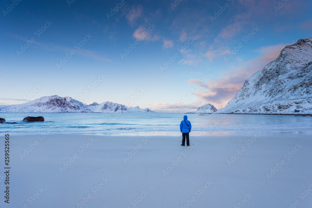 A man stands on the ocean in winter in Norway in the Lofoten Islands