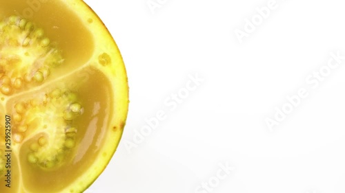Macro shooting, solanum quitoense naranjilla fruit sliced in half rotating on the white background, half filled frame photo