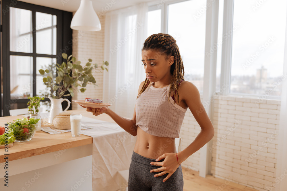 Dark-eyed woman leading healthy lifestyle not eating doughnut Dark-eyed woman leading healthy lifestyle not eating doughnut