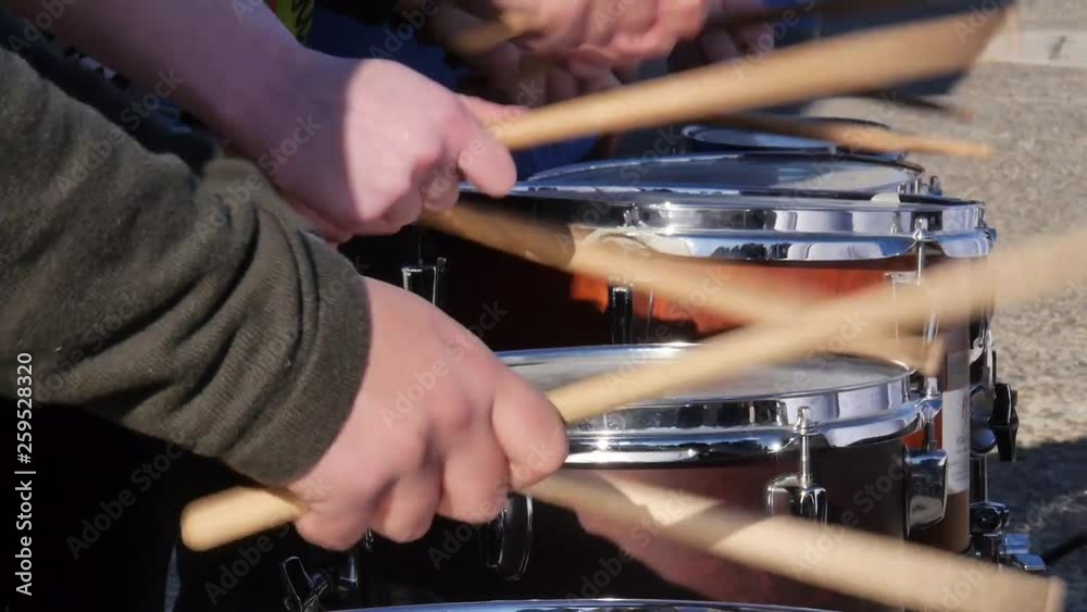 Close-up of many drummers in a line playing in unison