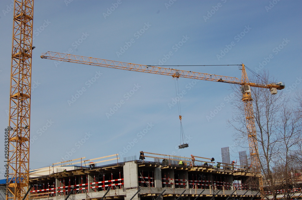 construction of a multistory residential concrete building and crane with cargo