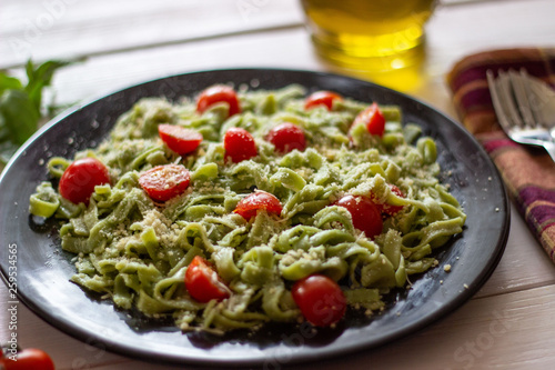 Green pasta with tomatoes and parmesan cheese. White background.