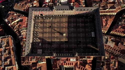 The Plaza Mayor in Madrid in an aerial shot. Teh camera rises and flys backwards on a sunny day. The roofs of Madrid can be seen from above. photo