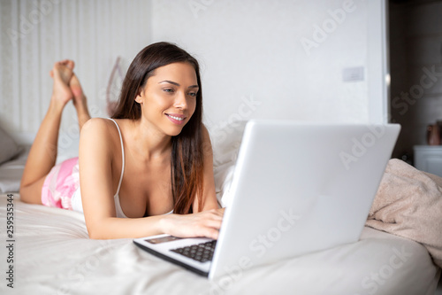 Sweet sexy lady using her laptop from bed