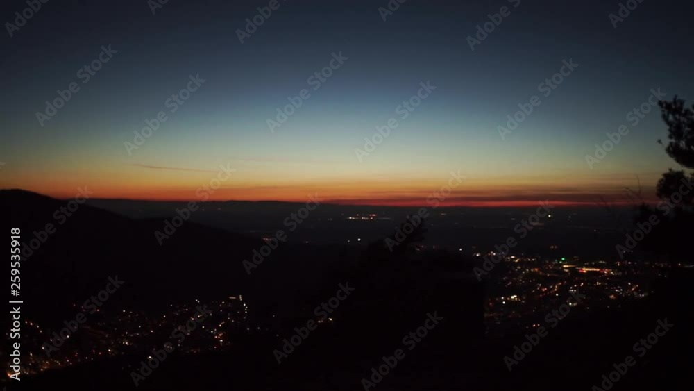 Camera pans left, showing city lights in the dark and the horizon which is illuminated by the beautiful blue hour light. Camera pans left, showing city lights in the dark and the horizon which is illuminated by the beautiful blue hour light.