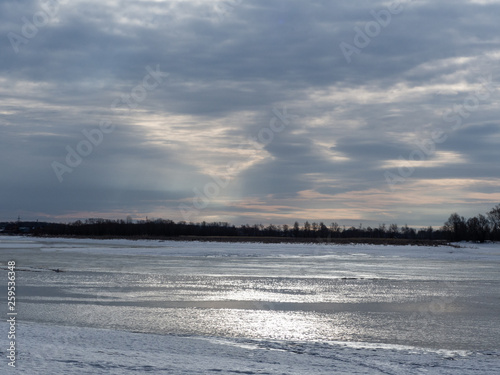 River in the early spring morning. The sun s rays pass through the clouds and illuminate the river. Ice descends from the river.