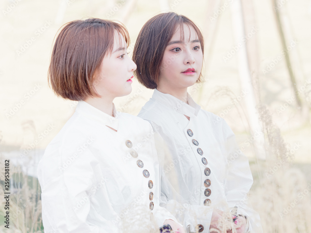 Beautiful young brunette woman in white shirt posing with herself in mirror like twins.Outdoor fashion portrait of glamour Chinese cheerful stylish girl, emotions, people, beauty and lifestyle concept Beautiful young brunette woman in white shirt posing with herself in mirror like twins.Outdoor fashion portrait of glamour Chinese cheerful stylish girl, emotions, people, beauty and lifestyle concept