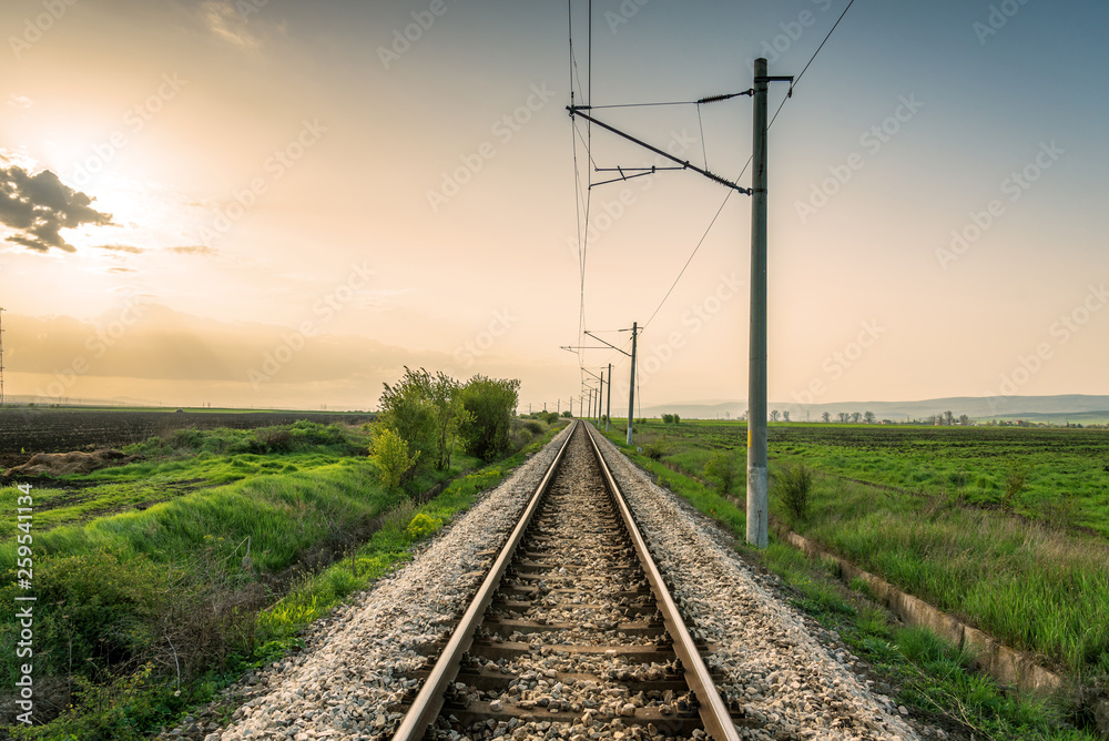 Orange sunset in low clouds over railroad.