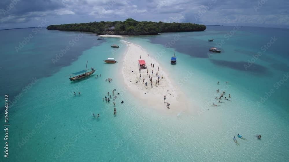 Group of people playing beachvolley on a tropical lone sand island.. Drone pull away shot