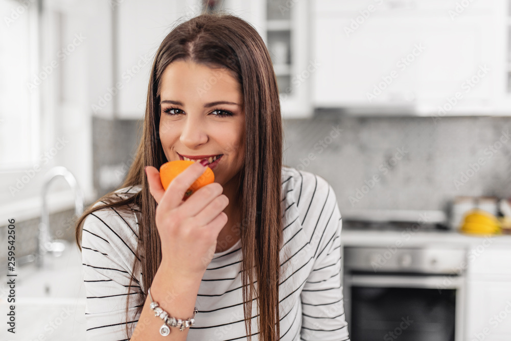 Pretty brunette holding orange halve and smiling at camera on white background Pretty brunette holding orange halve and smiling at camera on white background