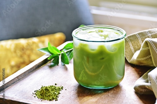 Glass of iced matcha green tea latte on the light home background 