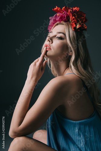 beautiful and blonde woman in elegant dress and wreath looking away isolated on black