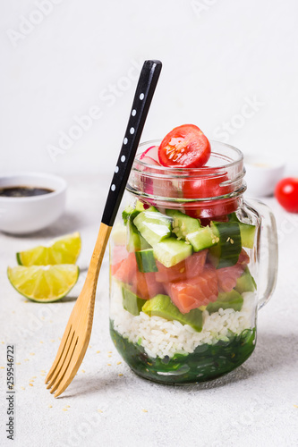 Hawaiian salmon poke salad in glass jar and bamboo fork, selective focus photo