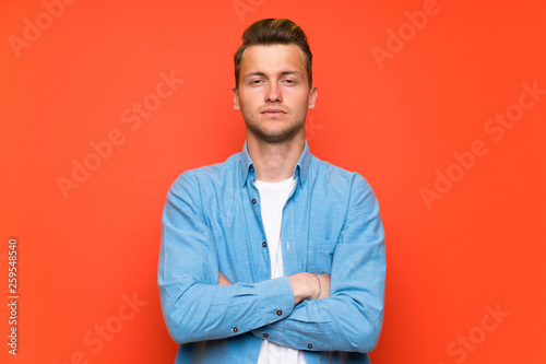 Blonde handsome man over isolated wall keeping arms crossed