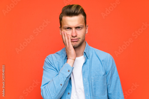 Blonde handsome man over isolated wall unhappy and frustrated