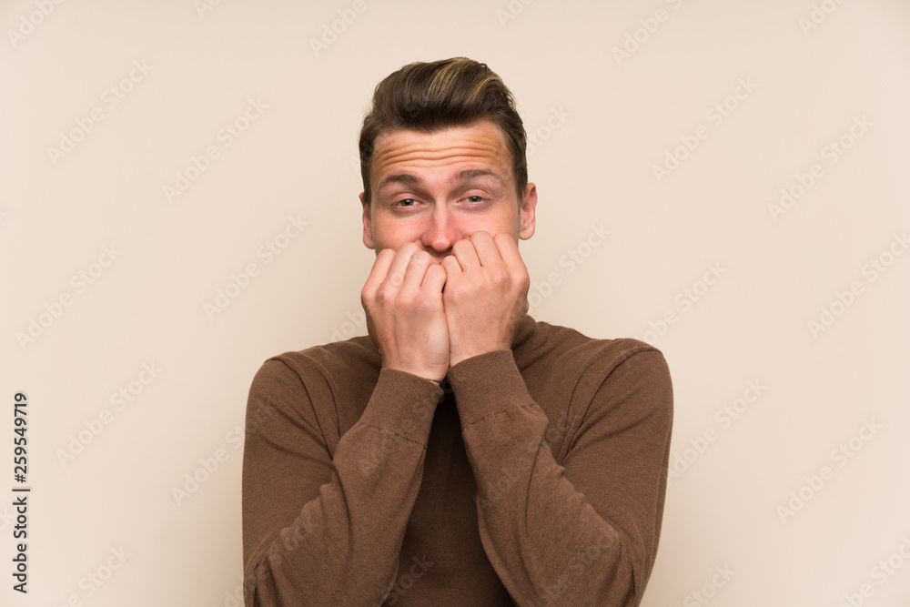 Blonde handsome man over isolated wall nervous and scared Blonde handsome man over isolated wall nervous and scared